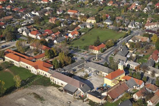 A kép hátterében az iskola,  előterében az egykori tsz-tulajdon és a felújított, egyházi tulajdonban lévő templom
